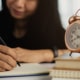 woman writing notebook with alarm-clock